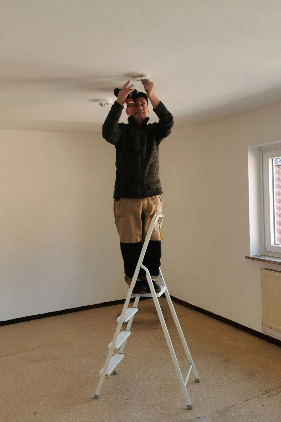 Fitting a ceiling detector from a step ladder, for ceiling fan installation in Vancouver