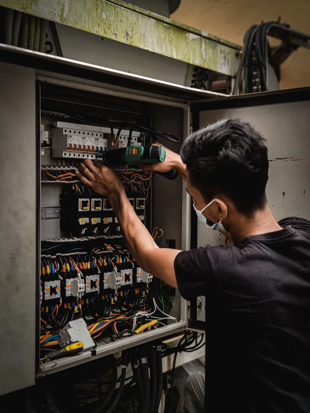 An electrician working inside a large distribution board, for commercial electrical in Vancouver