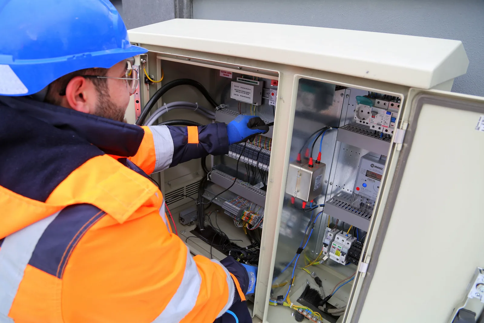 An electrician working in an outdoor service cabinet, for maintenance plans in Vancouver